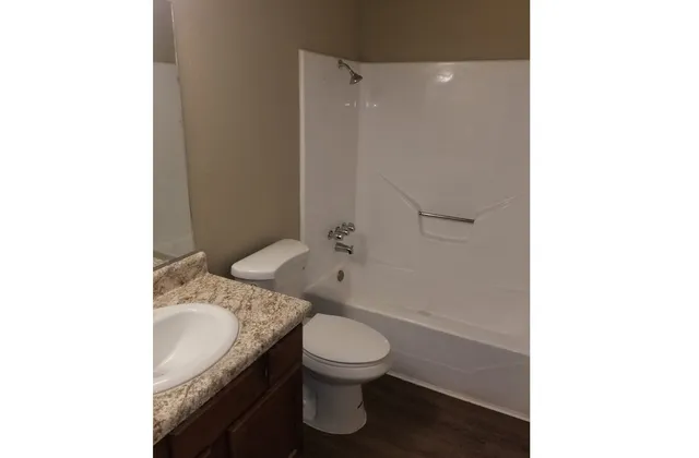 a bathroom with a granite countertop toilet a sink and a mirror