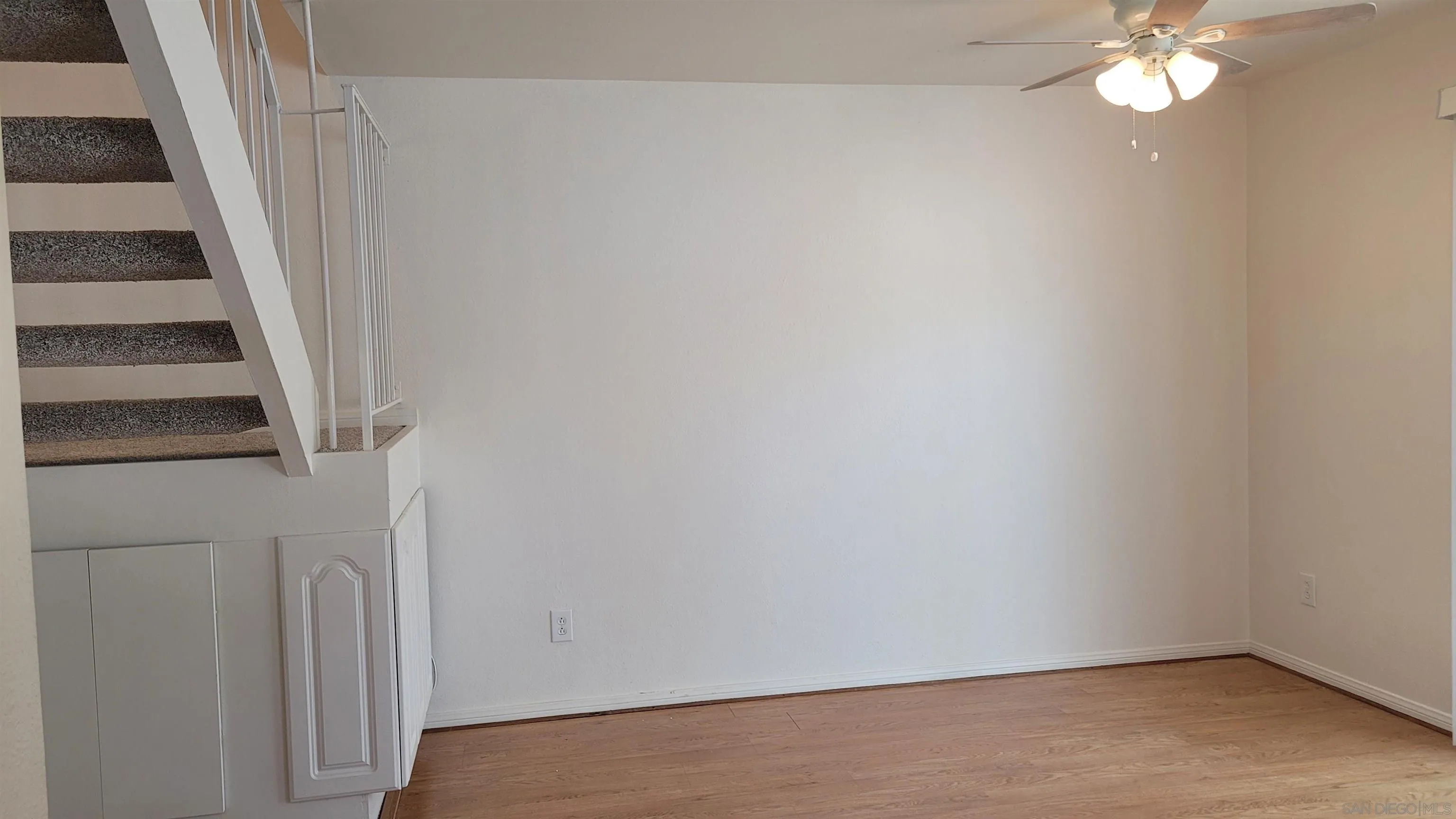 863 Del Mar Downs Road, Unit D Solana Beach, CA 92075 - Photo 8 of 23 an empty room with wooden floor and staircase