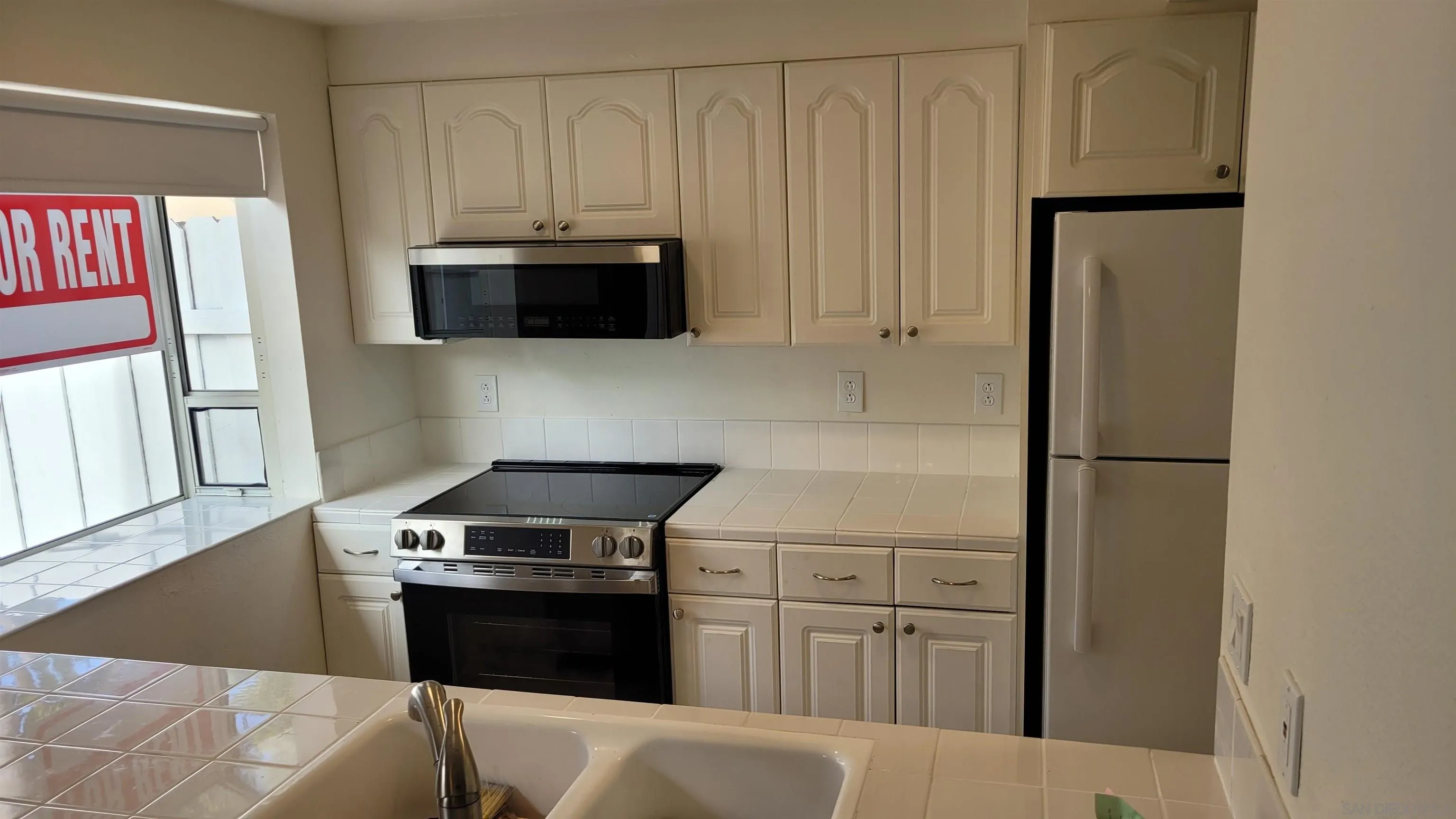 863 Del Mar Downs Road, Unit D Solana Beach, CA 92075 - Photo 10 of 23 a kitchen with white cabinets and black appliances