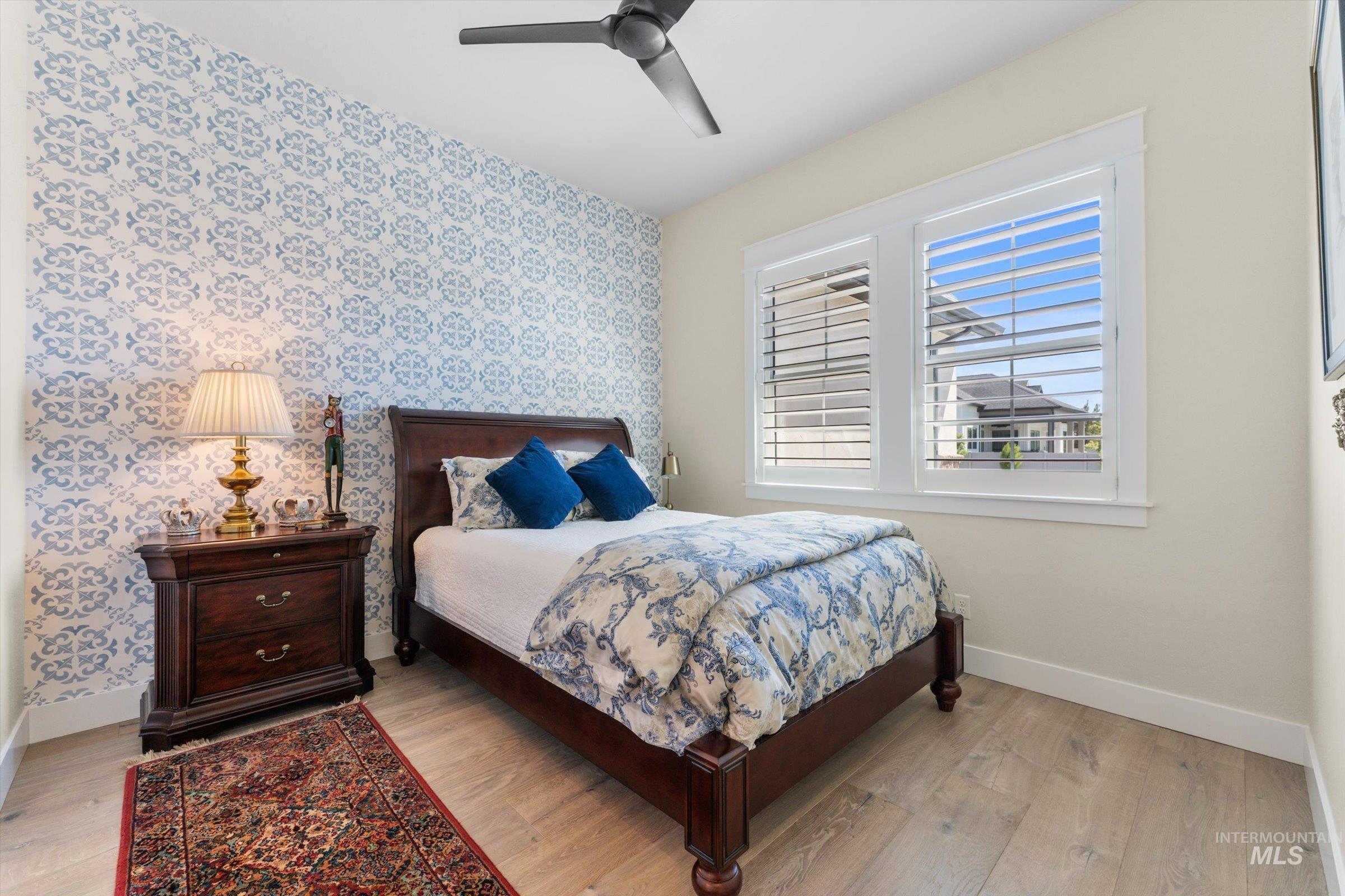 6585 South Pemberley Way Meridian, ID 83642 - Photo 30 of 43 Accent wall featuring a blue and white patterned design, complemented by wood-finish flooring