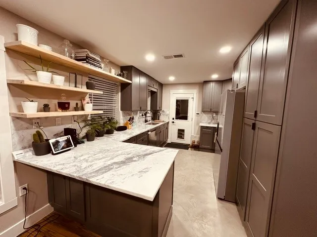 a kitchen with stainless steel appliances kitchen island granite countertop a refrigerator a sink a stove and island