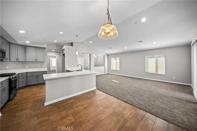 a large kitchen with a large counter top a sink stainless steel appliances and cabinets