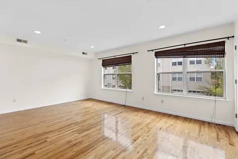a view of an empty room with a window and wooden floor