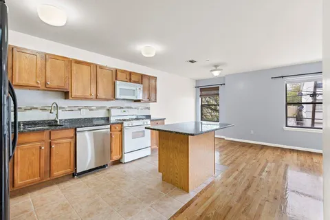 a kitchen with stainless steel appliances granite countertop a stove a sink dishwasher and a refrigerator with wooden floor