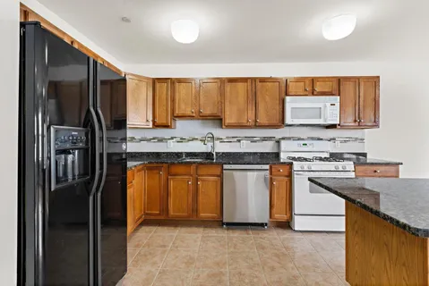 a kitchen with stainless steel appliances granite countertop a stove a sink and a refrigerator
