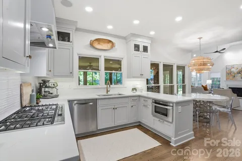 a kitchen with kitchen island granite countertop a stove a refrigerator a sink a island and a view of living room