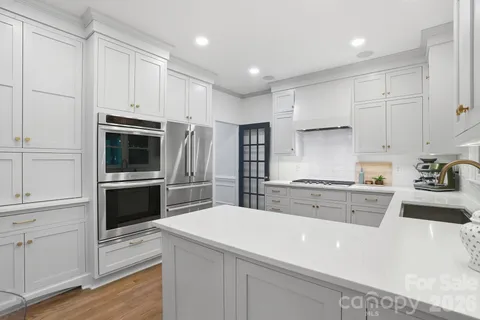a open kitchen with stainless steel appliances granite countertop a stove and a dining table with chairs