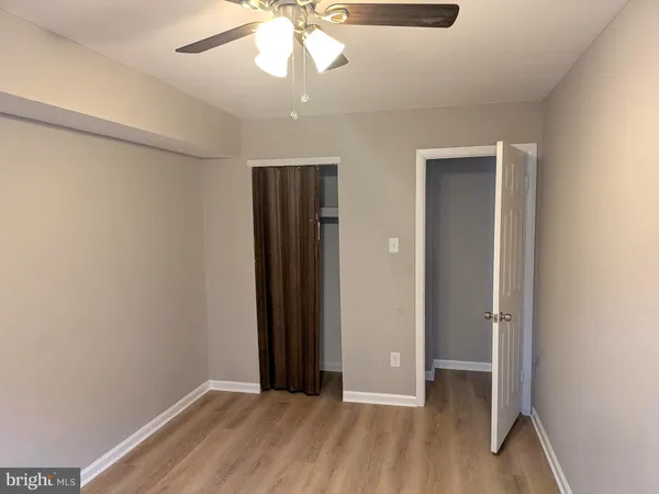 an empty room with wooden floor closet and windows