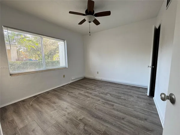 a view of empty room with wooden floor and fan