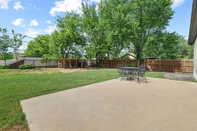 a patio with table and chairs and potted plants