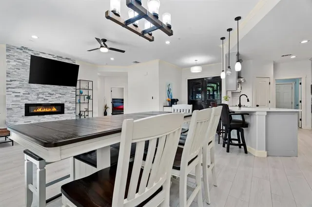 a kitchen with stainless steel appliances kitchen island granite countertop a stove a microwave a island a dining table and chairs with wooden floor