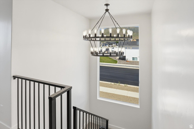 1315 West 3200 South, Unit 17 Perry, UT 84302 - Photo 24 of 58 Two-tiered chandelier illuminating a contemporary staircase with black metal railings and a large picture window