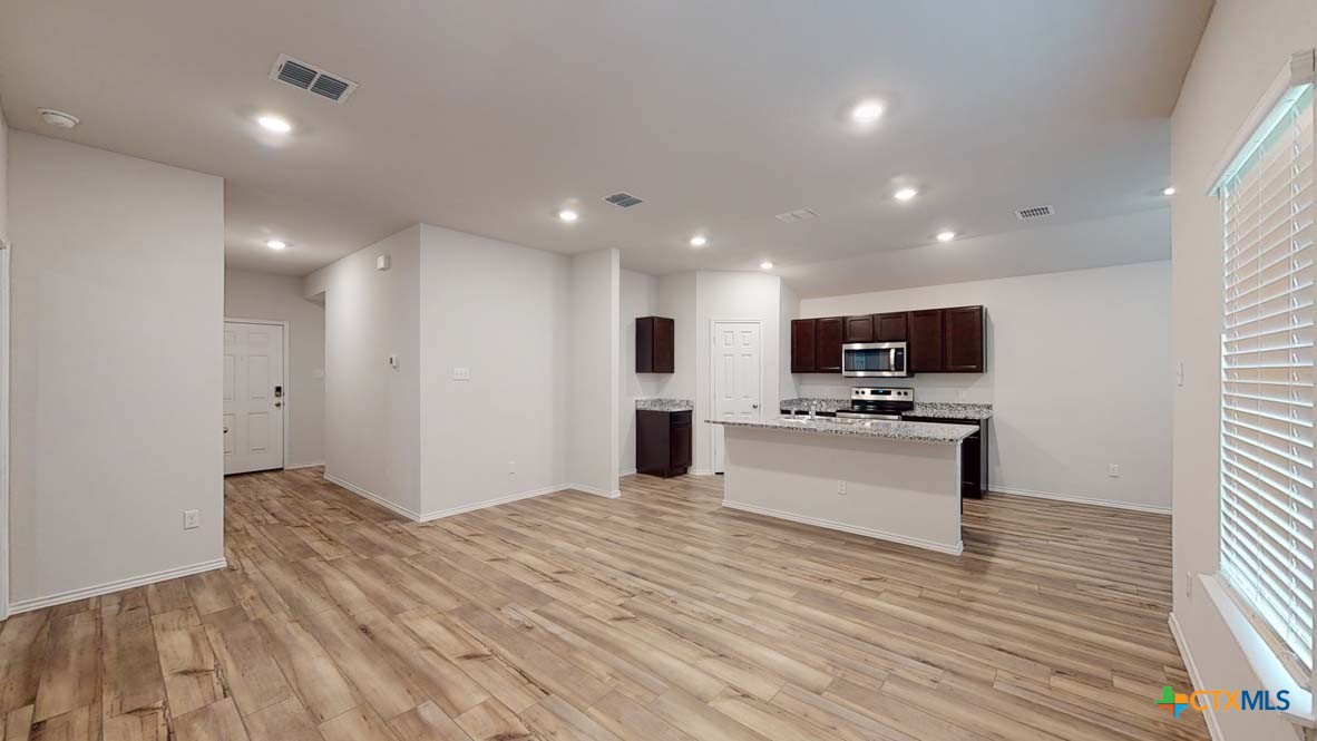 553 Hector Loop Georgetown, TX 78626 - Photo 4 of 21 a view of kitchen with kitchen island stainless steel appliances refrigerator stove microwave and stove with wooden floor