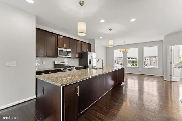 a large kitchen with stainless steel appliances granite countertop a sink a stove and a wooden floors
