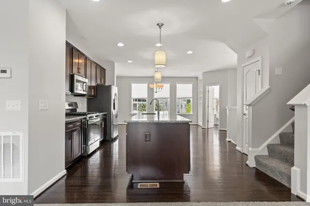 a view of a kitchen with a stove top oven a refrigerator with wooden floor