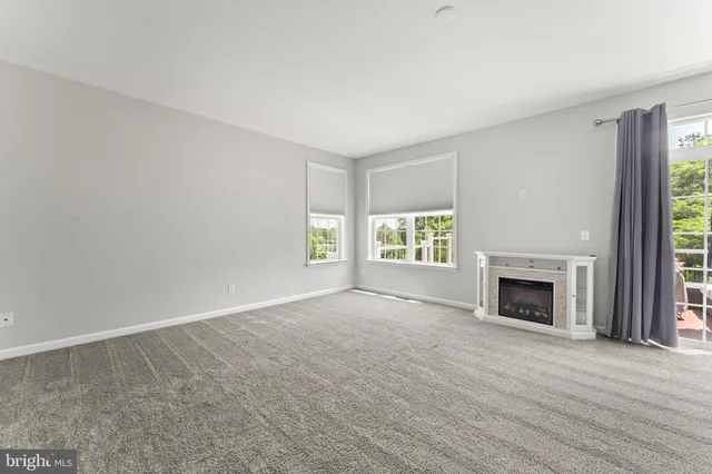 an empty room with windows and fireplace