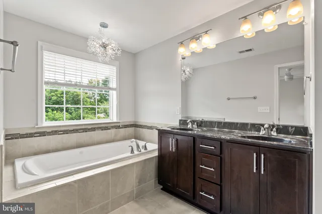a bathroom with a granite countertop bathtub a double vanity sink and a mirror