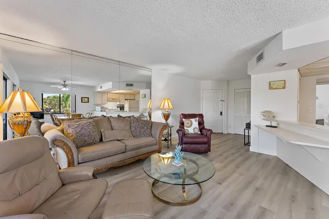 a living room with furniture kitchen view and a large window