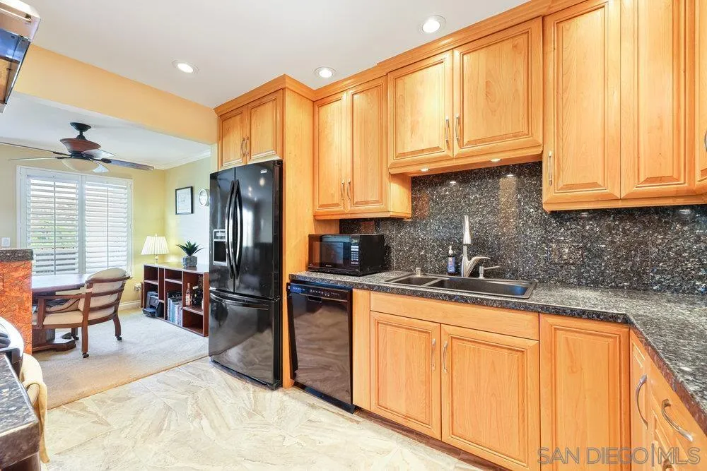 6780 Mission Gorge Road, Unit 12 San Diego, CA 92120 - Photo 2 of 23 a kitchen with stainless steel appliances granite countertop a refrigerator a sink dishwasher a stove and a dining table with wooden cabinet