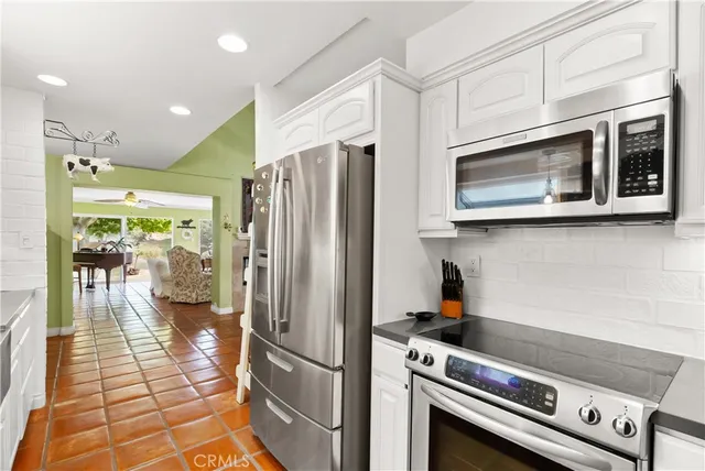 a kitchen with stainless steel appliances granite countertop a refrigerator a stove and a sink with cabinets