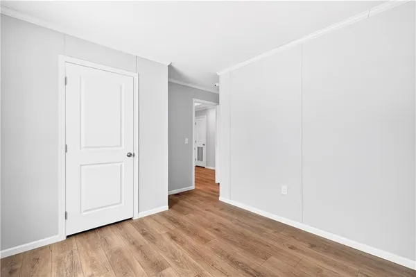 a view of an empty room with wooden floor and closet