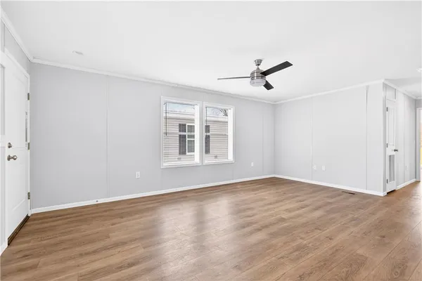 an empty room with wooden floor ceiling fan and windows