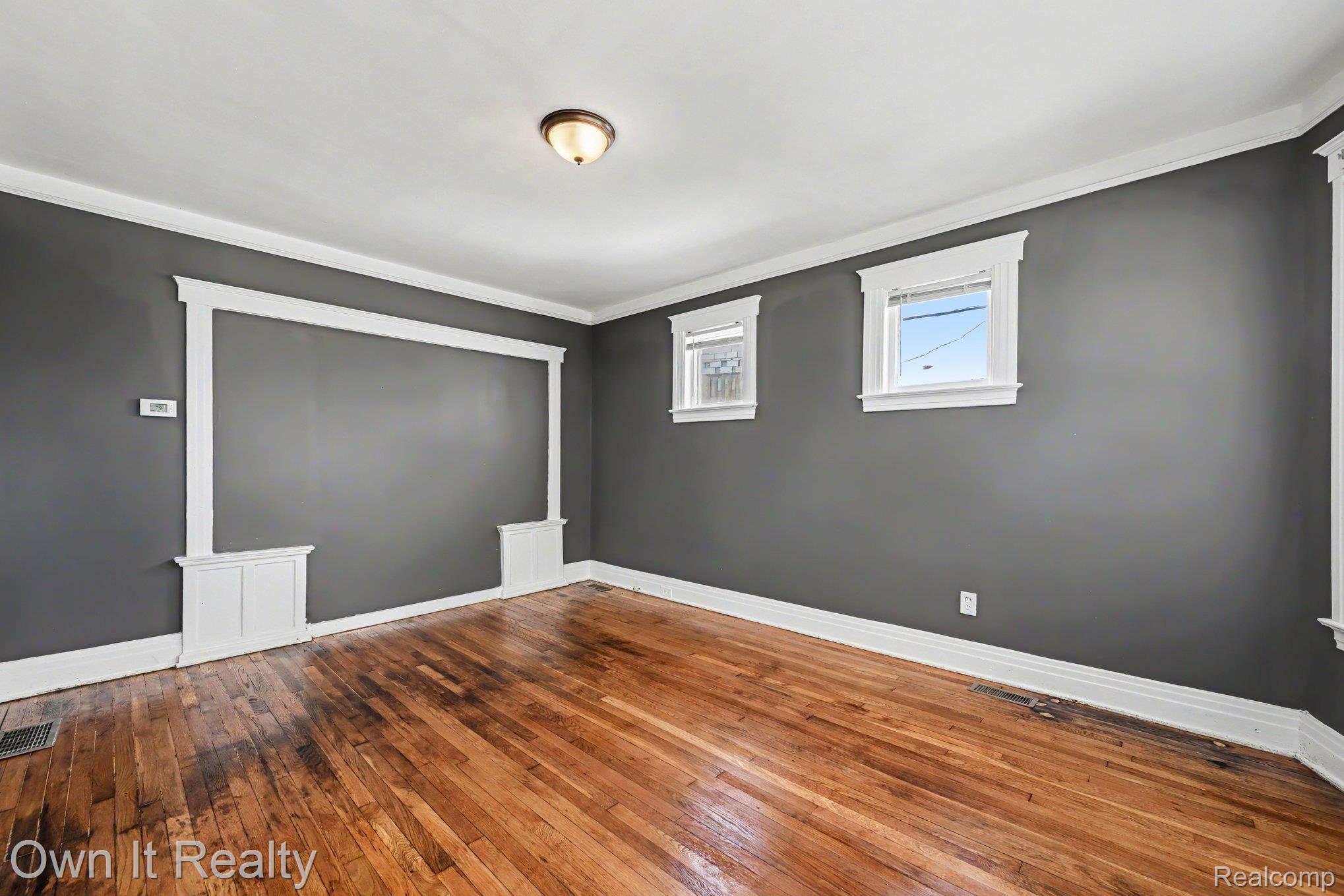 44 Maple Street River Rouge, MI 48218 - Photo 11 of 33 Hardwood flooring, decorative wall trim, two windows with white trim, and a ceiling-mounted light fixture