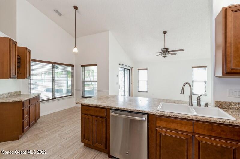 711 Montclair Road Northeast Palm Bay, FL 32905 - Photo 14 of 35 a kitchen with stainless steel appliances granite countertop a sink a stove and a wooden floors