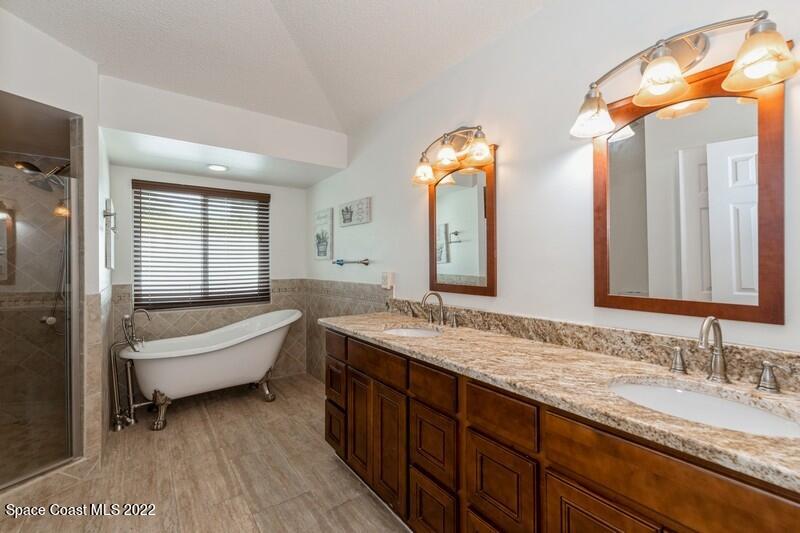 711 Montclair Road Northeast Palm Bay, FL 32905 - Photo 21 of 35 a bathroom with a granite countertop tub a double vanity sink and a large mirror