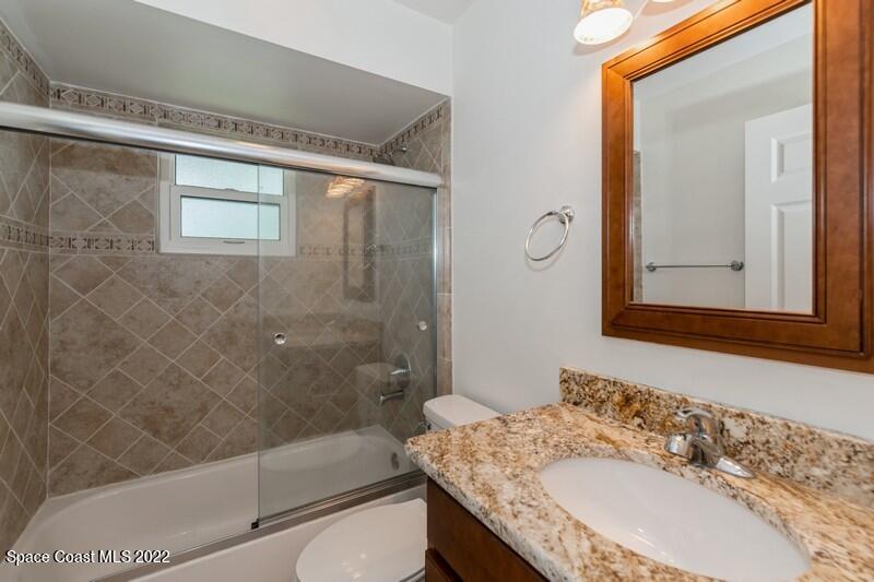 711 Montclair Road Northeast Palm Bay, FL 32905 - Photo 26 of 35 a bathroom with a granite countertop sink a mirror and shower