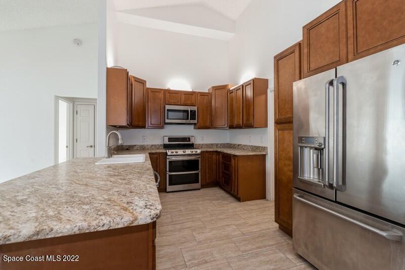 711 Montclair Road Northeast Palm Bay, FL 32905 - Photo 8 of 35 a kitchen with granite countertop a refrigerator stove and microwave
