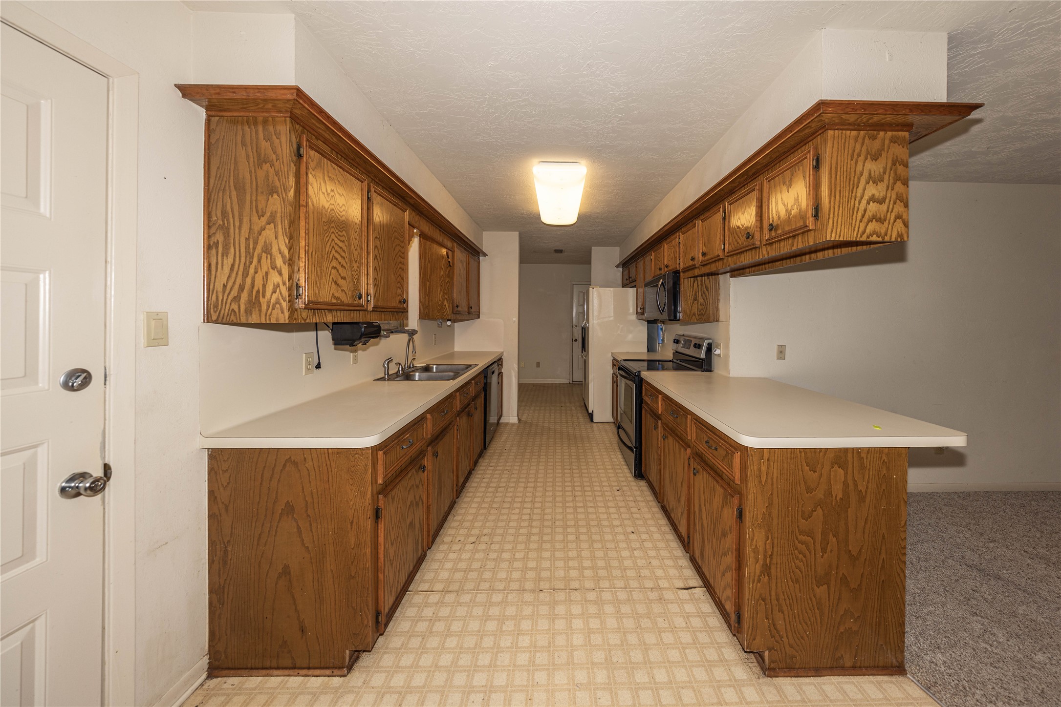 2501 Fischer Store Road Wimberley, TX 78676 - Photo 5 of 23 Galley kitchen featuring wood-finish cabinetry, white countertops, a double basin sink, and integrated appliances