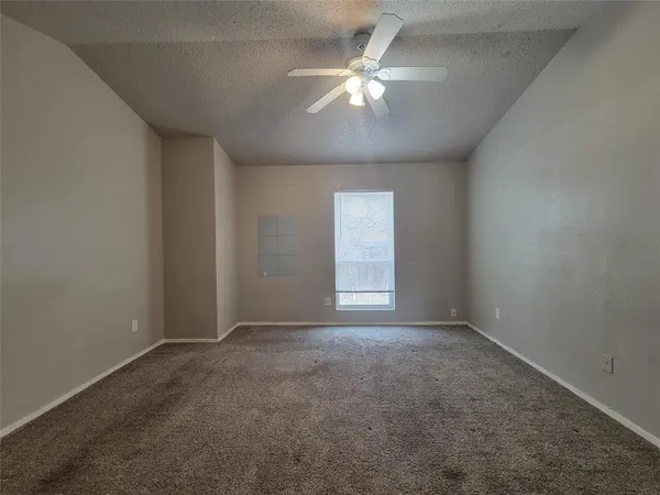 an empty room with a chandelier fan and windows