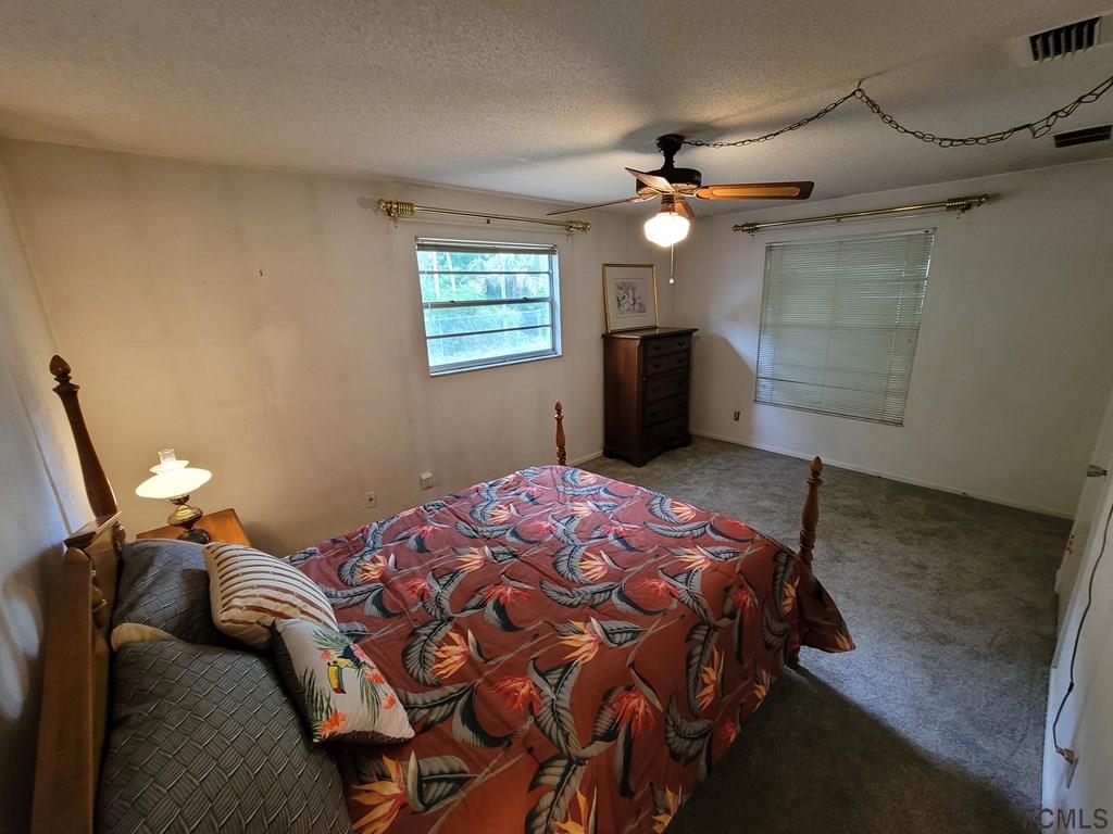 736 Lindenwood Circle Ormond Beach, FL 32174 - Photo 19 of 56 a bedroom with a bed and a chandelier