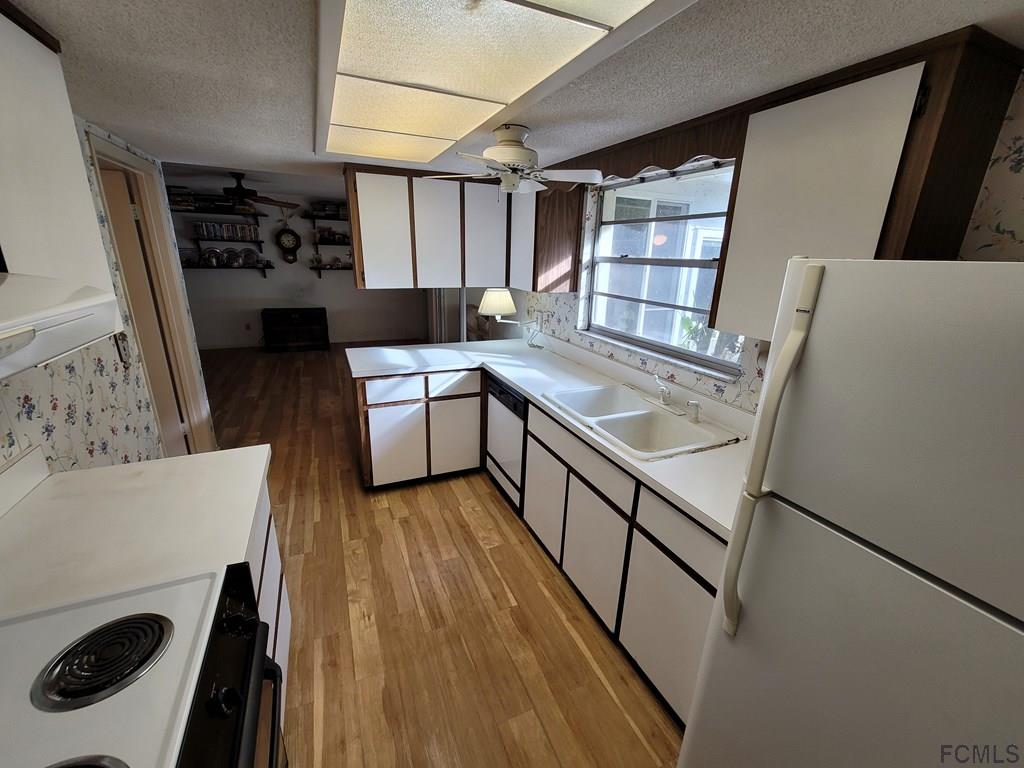 736 Lindenwood Circle Ormond Beach, FL 32174 - Photo 45 of 56 a kitchen with stainless steel appliances granite countertop a refrigerator a stove and a sink with wooden floor
