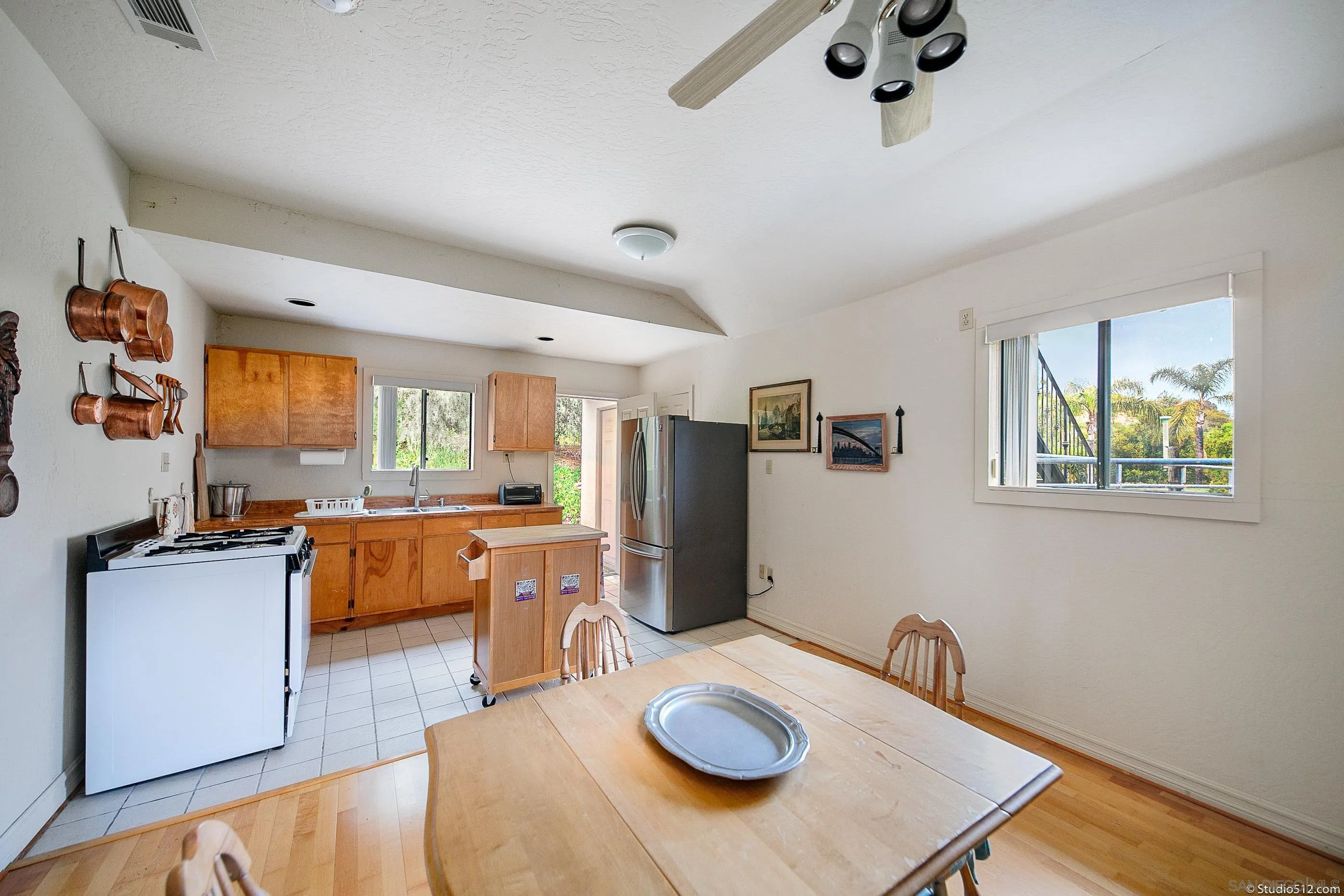 28398 Alamar Road Valley Center, CA 92082 - Photo 29 of 41 a kitchen with stainless steel appliances kitchen island granite countertop a refrigerator a stove a sink a dining table and chairs with wooden floor