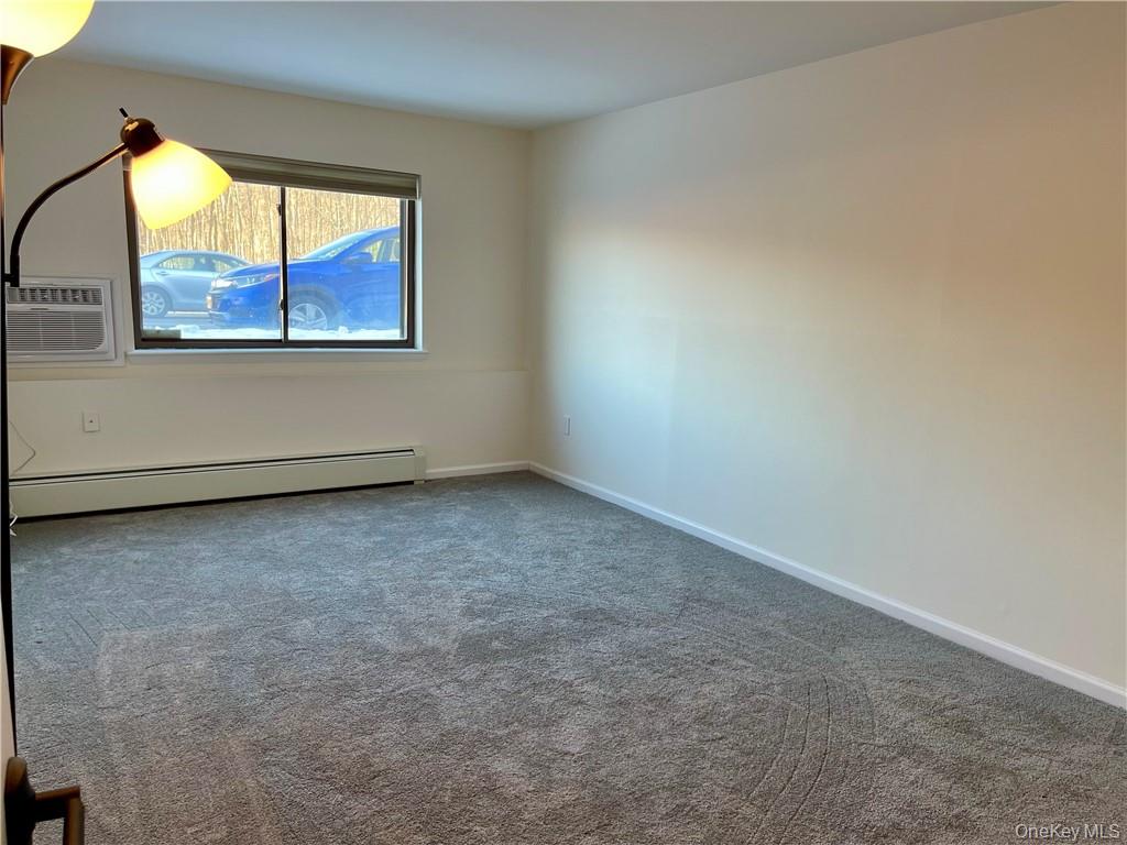 27 Tanager Road, Unit 2702 Monroe, NY 10950 - Photo 15 of 17 Neutral wall paint, gray carpet flooring, horizontal window, baseboard heating, and a window-mounted air conditioning unit