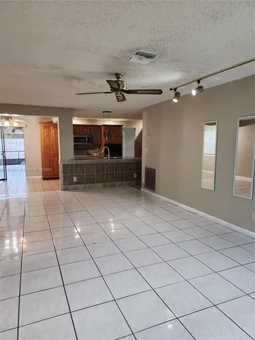 a view of empty room with kitchen and window
