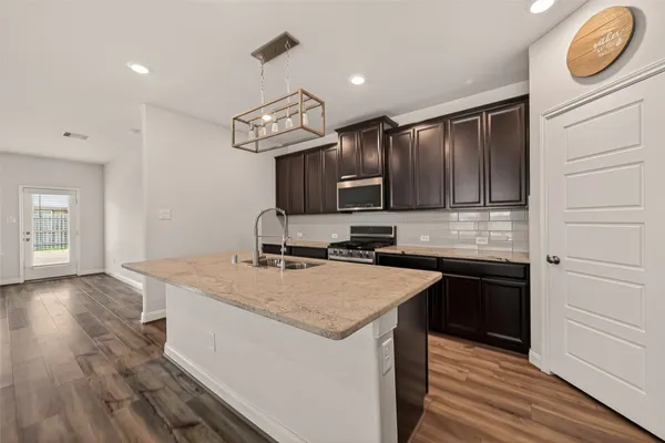 a kitchen with granite countertop a sink a counter space appliances and cabinets