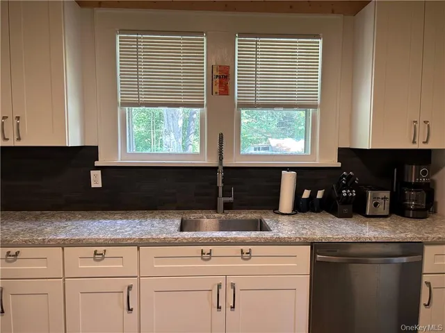 a kitchen with granite countertop white cabinets and black stainless steel appliances