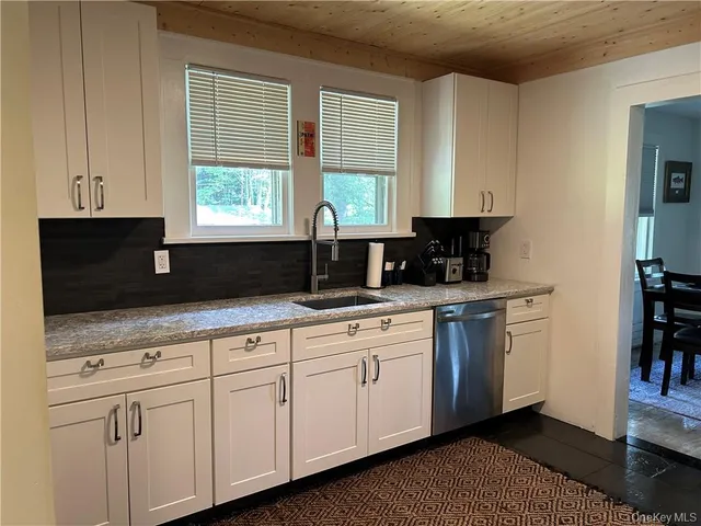 a kitchen with stainless steel appliances granite countertop white cabinets sink and window