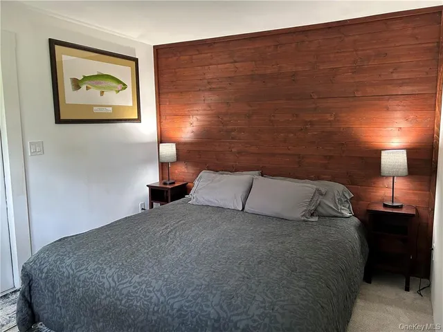 a bedroom with a bed and a lamp on dresser