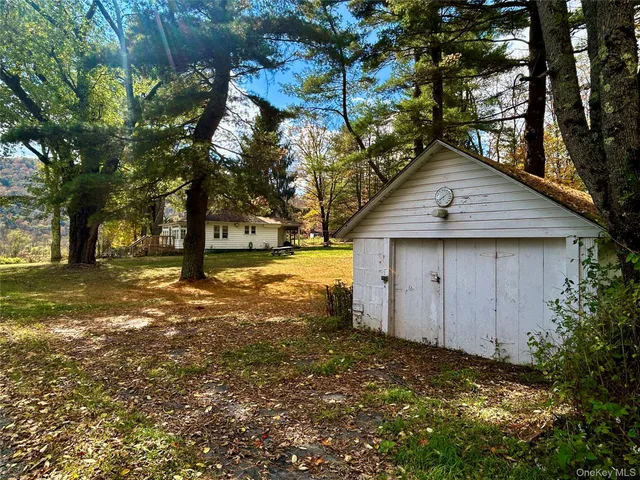 a backyard of a house with large trees and a small barn