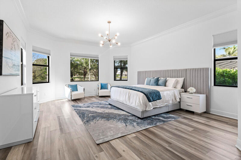 12153 Boca Reserve Lane Boca Raton, FL 33428 - Photo 12 of 35 a spacious bedroom with a large bed a chandelier and windows