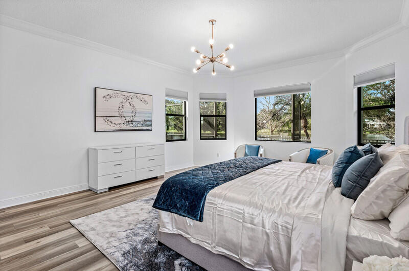 12153 Boca Reserve Lane Boca Raton, FL 33428 - Photo 13 of 35 a bedroom with a large bed a chandelier and window