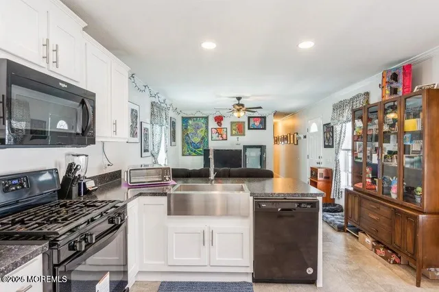 a kitchen with stainless steel appliances granite countertop a stove top oven a sink dishwasher and a microwave with wooden floor