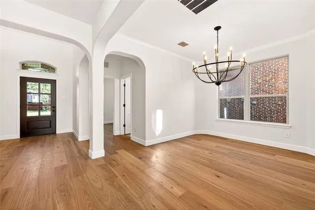 a view of empty room with wooden floor and pendant lights