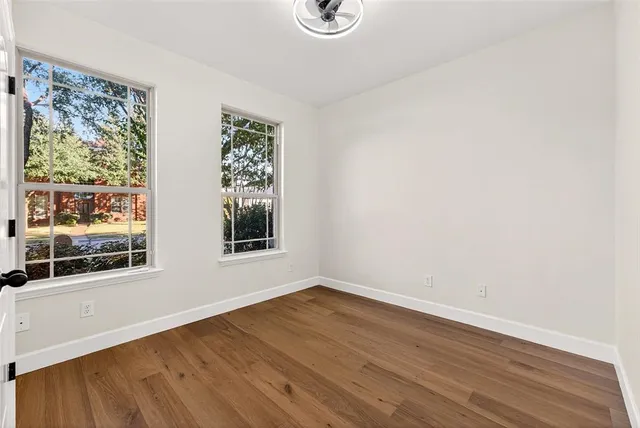 a view of an empty room with wooden floor and a window