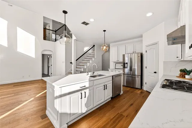 a kitchen with stainless steel appliances a stove a sink cabinets and wooden floor