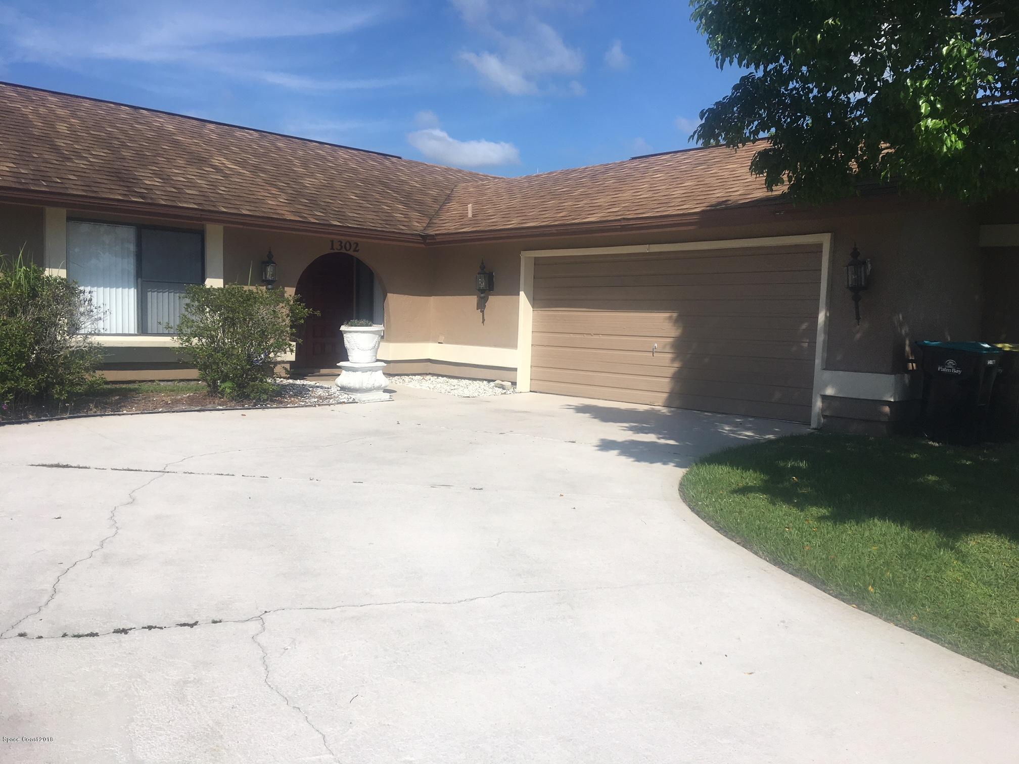 1302 Cherry Hills Road Northeast Palm Bay, FL 32905 - Photo 2 of 24 a front view of a house with a yard and garage